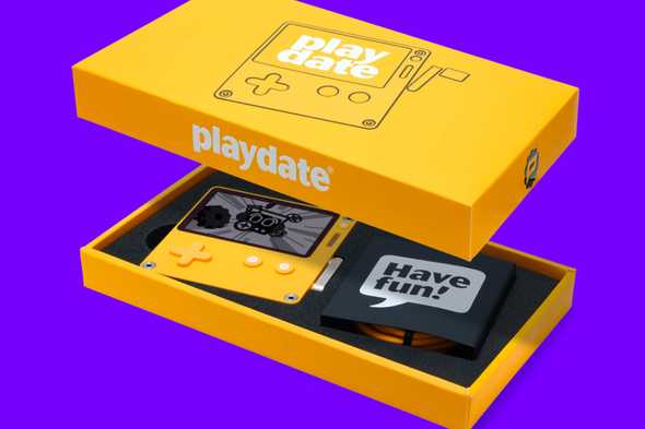 Playdate console in its yellow box, with a charging cable visible on a solid purple background.